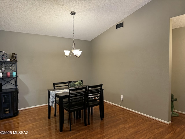dining space featuring a chandelier, a textured ceiling, wood finished floors, and visible vents