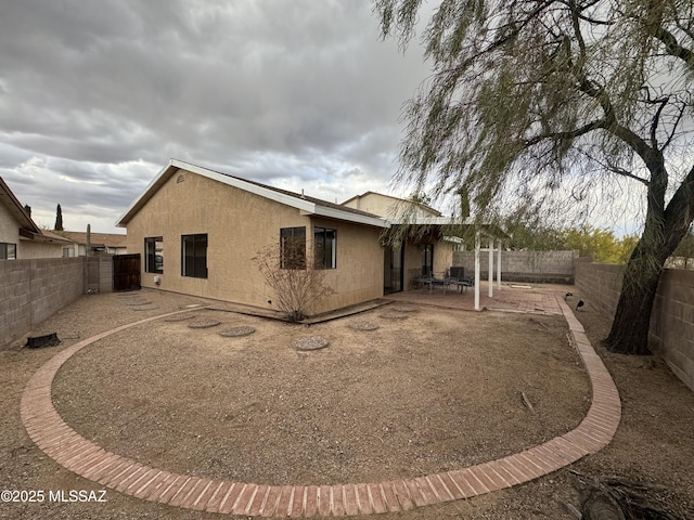 rear view of house with a fenced backyard, a patio area, and stucco siding
