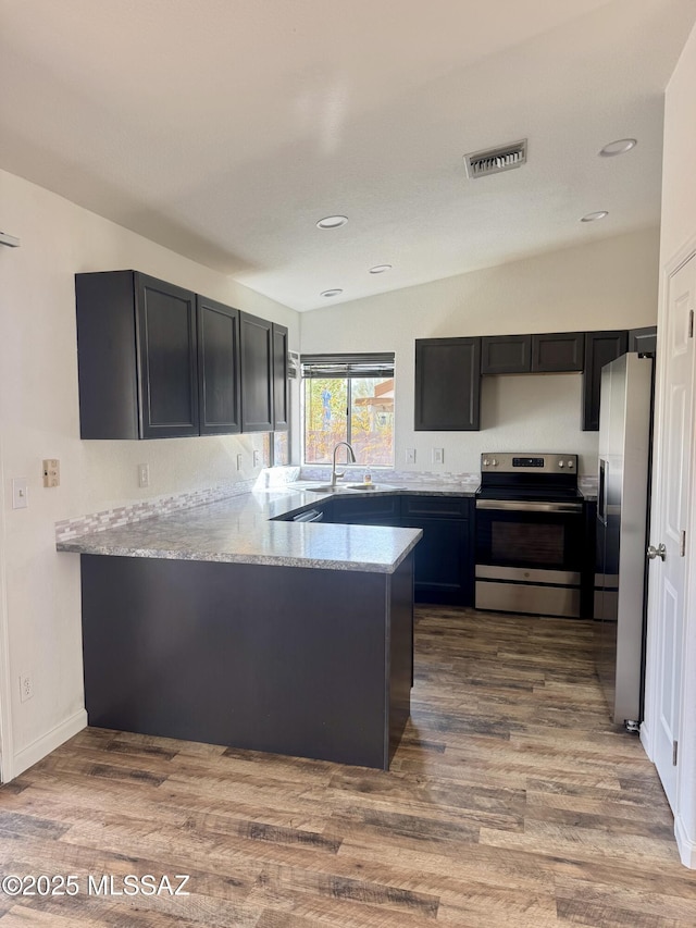 kitchen featuring visible vents, wood finished floors, a peninsula, stainless steel appliances, and recessed lighting