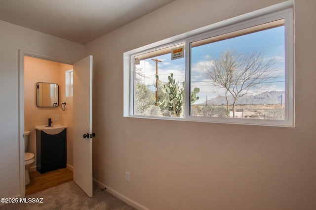 unfurnished bedroom featuring baseboards, carpet floors, connected bathroom, and a sink