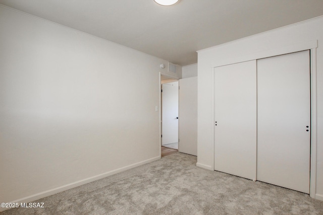 unfurnished bedroom with baseboards, a closet, carpet floors, and ornamental molding