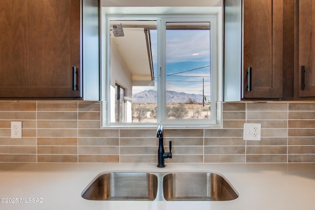 details featuring decorative backsplash, dark brown cabinetry, light countertops, and a sink