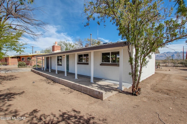 single story home with stucco siding and a chimney