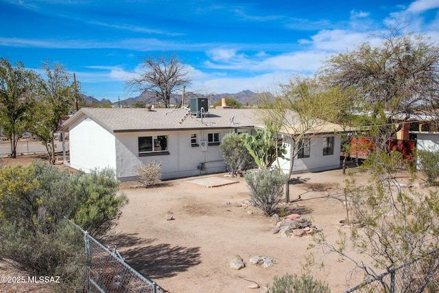 rear view of house featuring a patio area, stucco siding, fence, central AC unit, and a mountain view