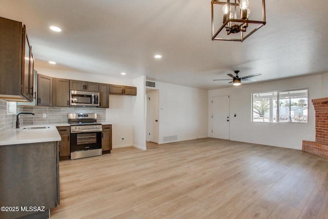 kitchen featuring a sink, tasteful backsplash, appliances with stainless steel finishes, light wood-style flooring, and visible vents
