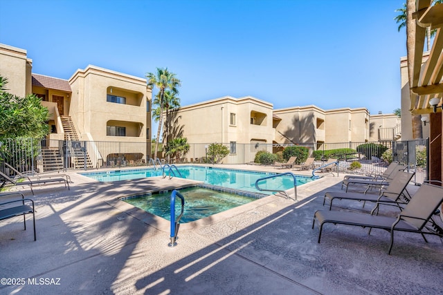 pool with a patio, fence, a community hot tub, and stairs
