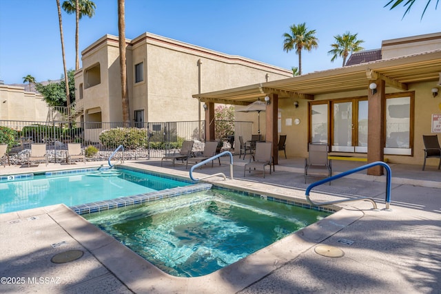 view of swimming pool featuring a community hot tub, a patio area, and fence