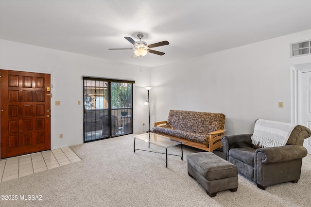 living area with carpet flooring, a ceiling fan, visible vents, and tile patterned flooring