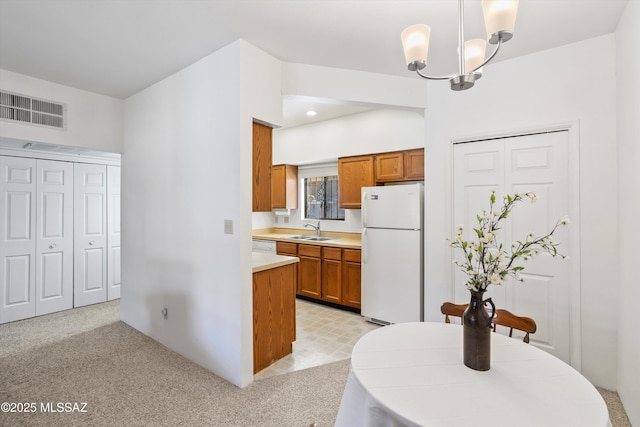 kitchen with brown cabinetry, a sink, white appliances, and visible vents