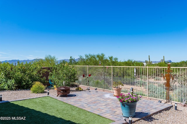 view of patio with a fire pit, a mountain view, and fence