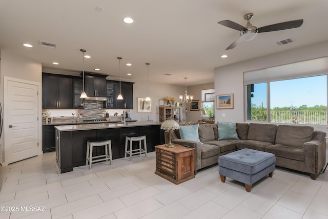 living room featuring ceiling fan with notable chandelier, light tile patterned floors, visible vents, and recessed lighting