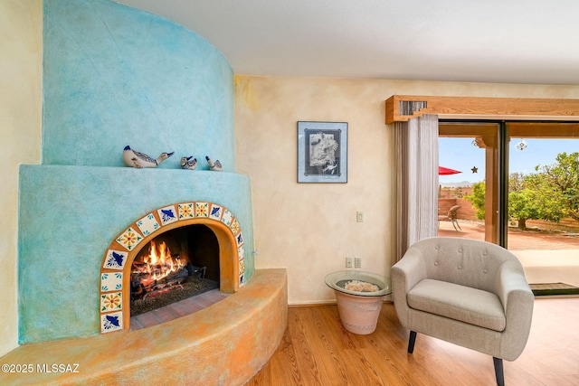 living area with baseboards, a lit fireplace, and wood finished floors
