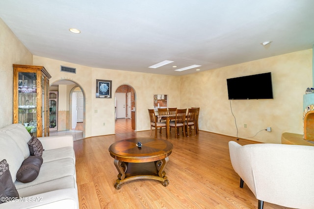living area with visible vents, wood finished floors, arched walkways, and recessed lighting
