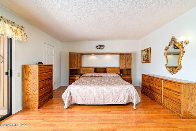 bedroom featuring baseboards, a textured ceiling, and light wood-style flooring