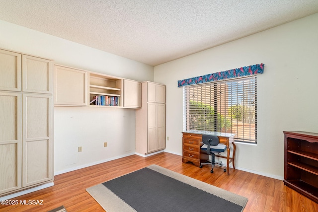 office space featuring a textured ceiling, baseboards, and light wood-type flooring