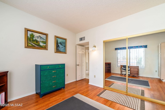 interior space featuring a closet, a textured ceiling, visible vents, and wood finished floors