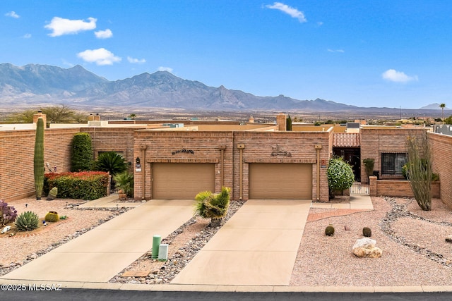 view of front of house with concrete driveway, fence, a mountain view, brick siding, and a chimney