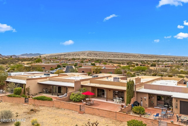 rear view of property featuring a chimney, stucco siding, a mountain view, and a patio