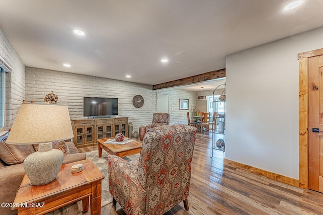 living room with baseboards, wood finished floors, recessed lighting, and brick wall