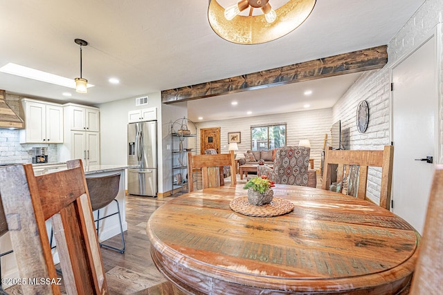 dining space with recessed lighting, light wood-type flooring, beamed ceiling, visible vents, and a fireplace