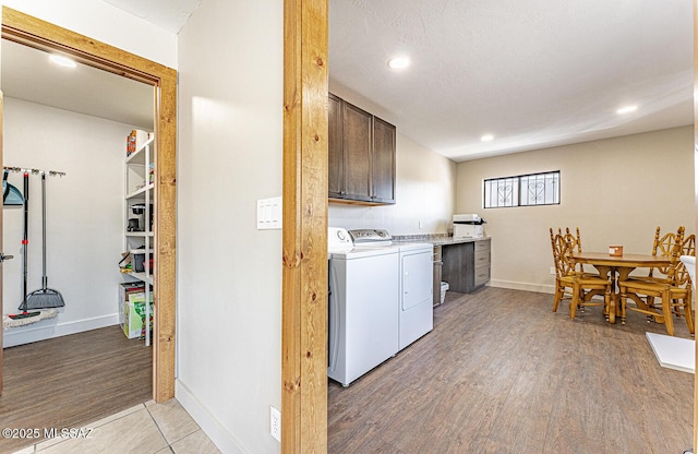 laundry room featuring independent washer and dryer, light wood-style floors, cabinet space, and baseboards