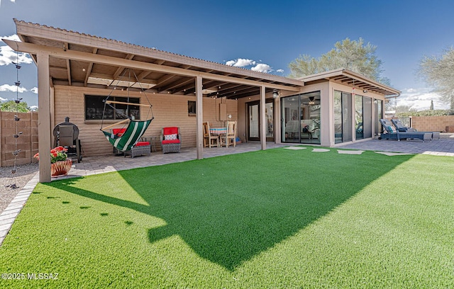 rear view of house featuring a patio, fence, and a yard
