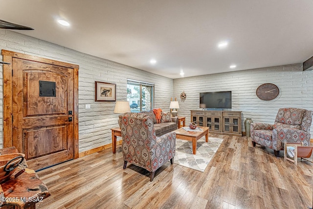 living area featuring light wood finished floors, brick wall, and recessed lighting