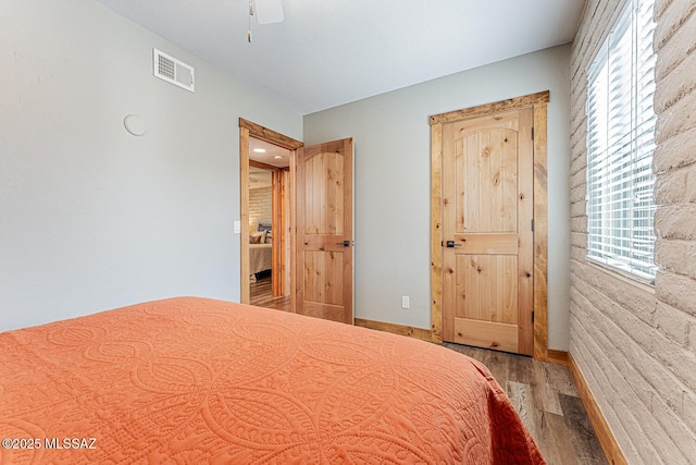 unfurnished bedroom with wood finished floors, baseboards, multiple windows, and visible vents