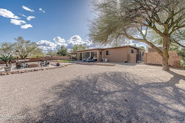 rear view of house featuring fence, a gate, a patio, and stucco siding