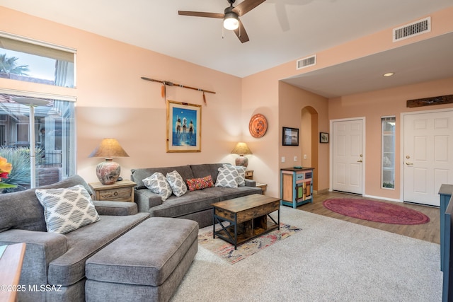 living area featuring arched walkways, visible vents, a ceiling fan, and wood finished floors