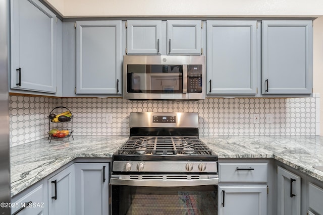 kitchen with appliances with stainless steel finishes, backsplash, and light stone countertops