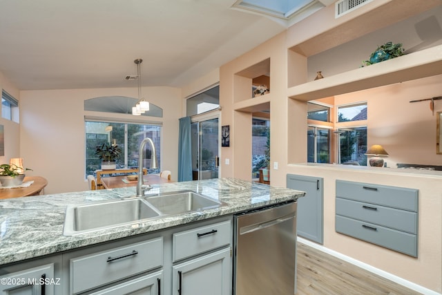 kitchen featuring light wood-style flooring, visible vents, dishwasher, a sink, and decorative light fixtures