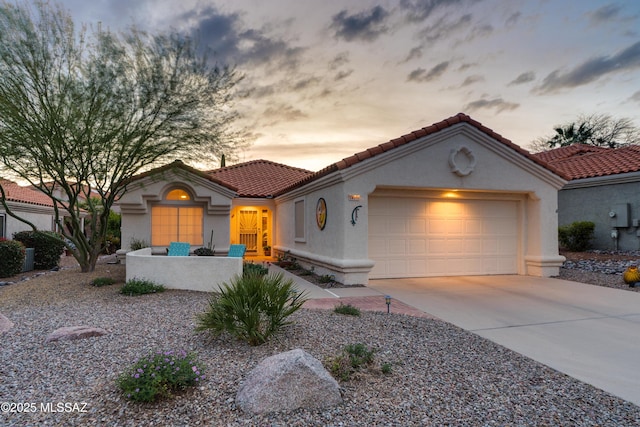 mediterranean / spanish house with a tiled roof, an attached garage, driveway, and stucco siding