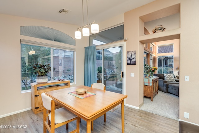 dining area with light wood-type flooring, visible vents, and a wealth of natural light