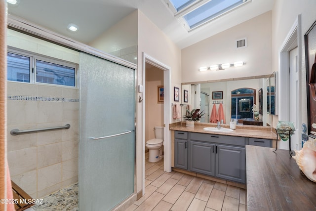 full bath with toilet, vaulted ceiling with skylight, wood tiled floor, and a stall shower