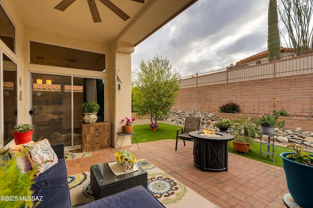 view of patio / terrace with an outdoor living space with a fire pit, a fenced backyard, and a ceiling fan