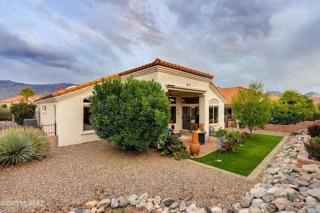 back of house with a tile roof, fence, a patio, and stucco siding