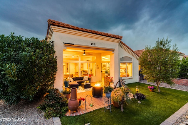back of property featuring an outdoor living space with a fire pit, a yard, stucco siding, a patio, and a tile roof