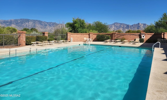 pool with a mountain view, fence, and a patio
