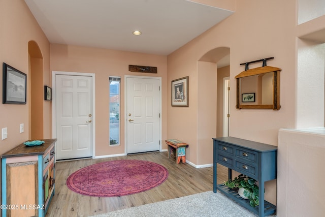 entryway with baseboards, recessed lighting, arched walkways, and wood finished floors