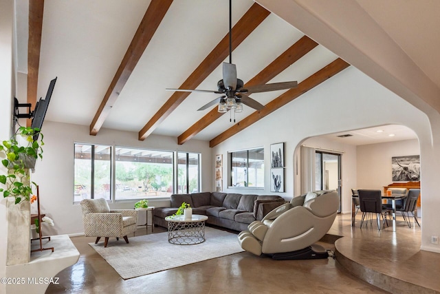 living room featuring arched walkways, beamed ceiling, finished concrete flooring, healthy amount of natural light, and ceiling fan