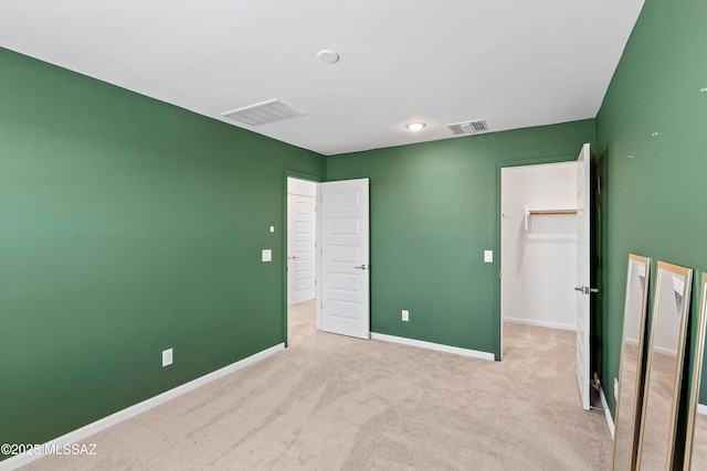 22082 E Thunderhead Dr, Red Rock, AZ 85145 - unfurnished bedroom featuring light colored carpet, baseboards, visible vents, and a walk in closet