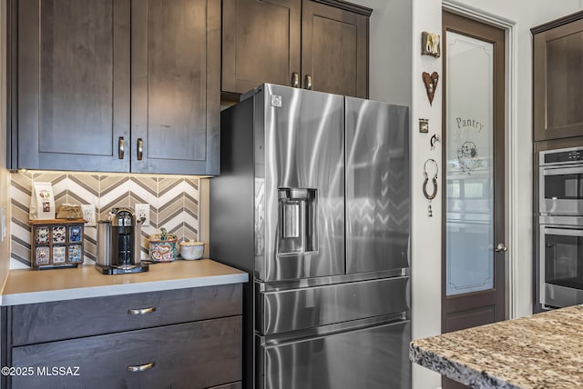 kitchen featuring backsplash, appliances with stainless steel finishes, and dark brown cabinets