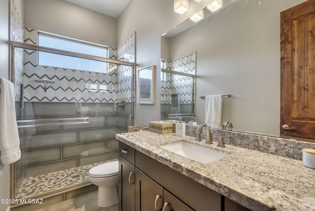 full bathroom featuring a stall shower, toilet, and vanity