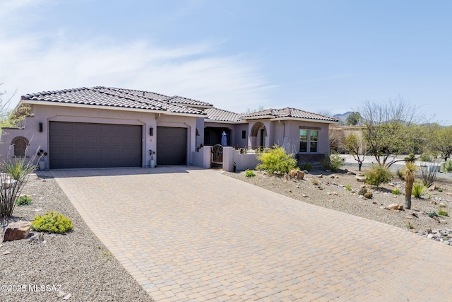 view of front of property featuring stucco siding, an attached garage, a tiled roof, and driveway