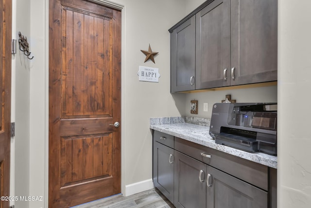 kitchen featuring light stone countertops, baseboards, and light wood-style floors