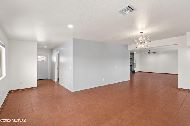 tiled empty room with baseboards, a textured ceiling, and visible vents