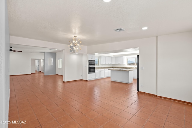 unfurnished living room featuring a textured ceiling, light tile patterned floors, baseboards, visible vents, and recessed lighting
