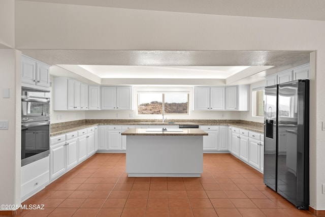kitchen featuring white cabinets, light tile patterned flooring, stainless steel appliances, and a tray ceiling