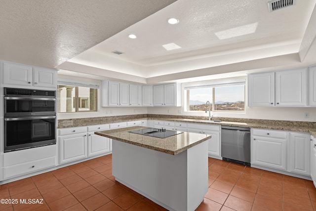 kitchen featuring light tile patterned floors, stainless steel appliances, a tray ceiling, and visible vents